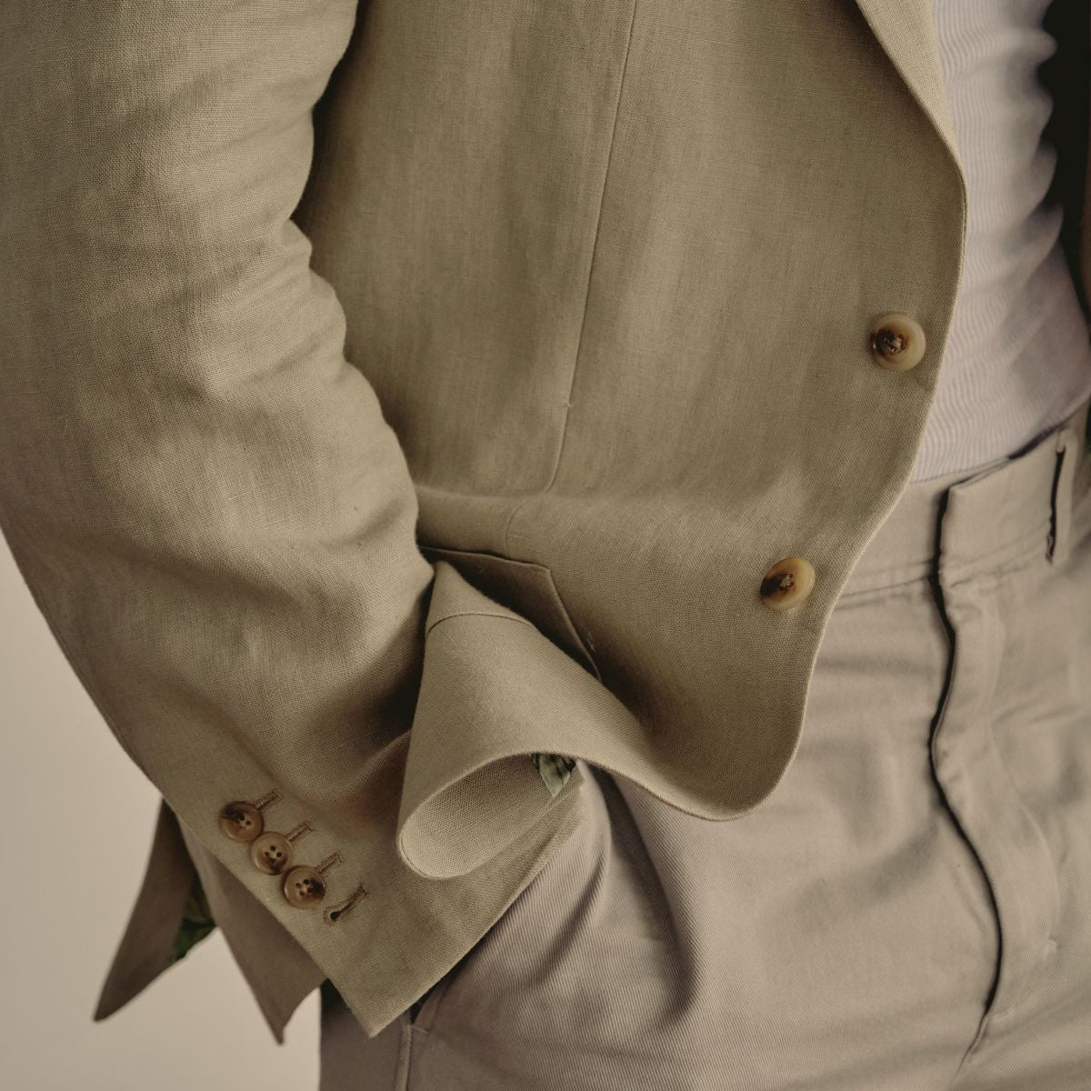 Close-up of a beige jacket with buttons on a neutral background made to measure